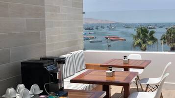 Un balcon avec un coin salon, une machine à café et une vue sur les bateaux qui naviguent.