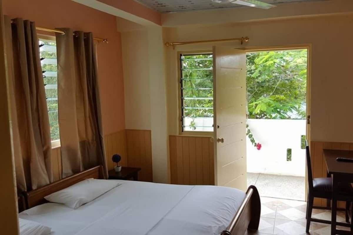 Ein Schlafzimmer mit Bett, Schreibtisch und einem Fenster mit Vorhängen.