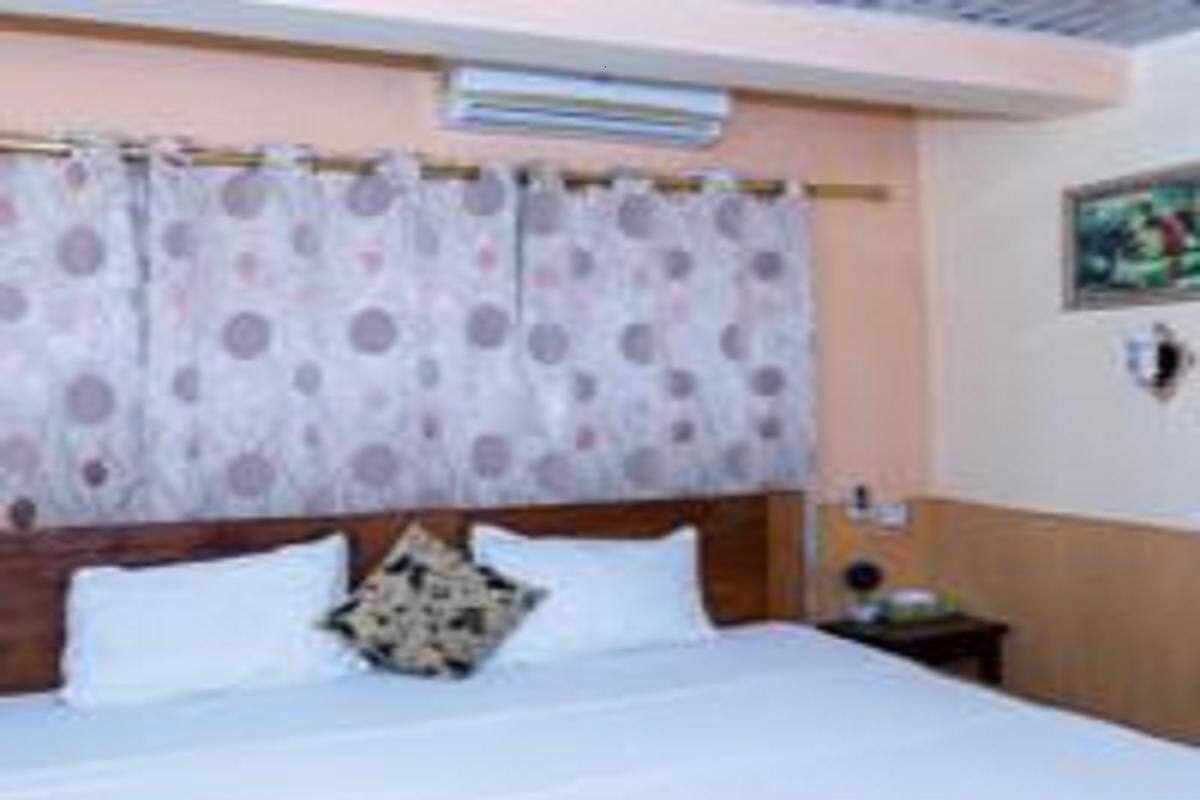 Ein Hotelzimmer mit Bett, Nachttisch und Wandklimaanlage.