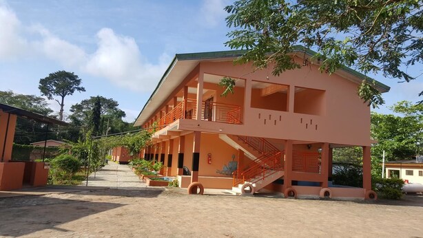 A multi-story building with balconies and a staircase. - Hans Cottage Botel (Cape Coast)