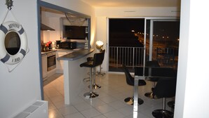 Eine moderne Küche mit Bar, einem Essbereich mit zwei Stühlen und Blick auf die beleuchtete Stadt.