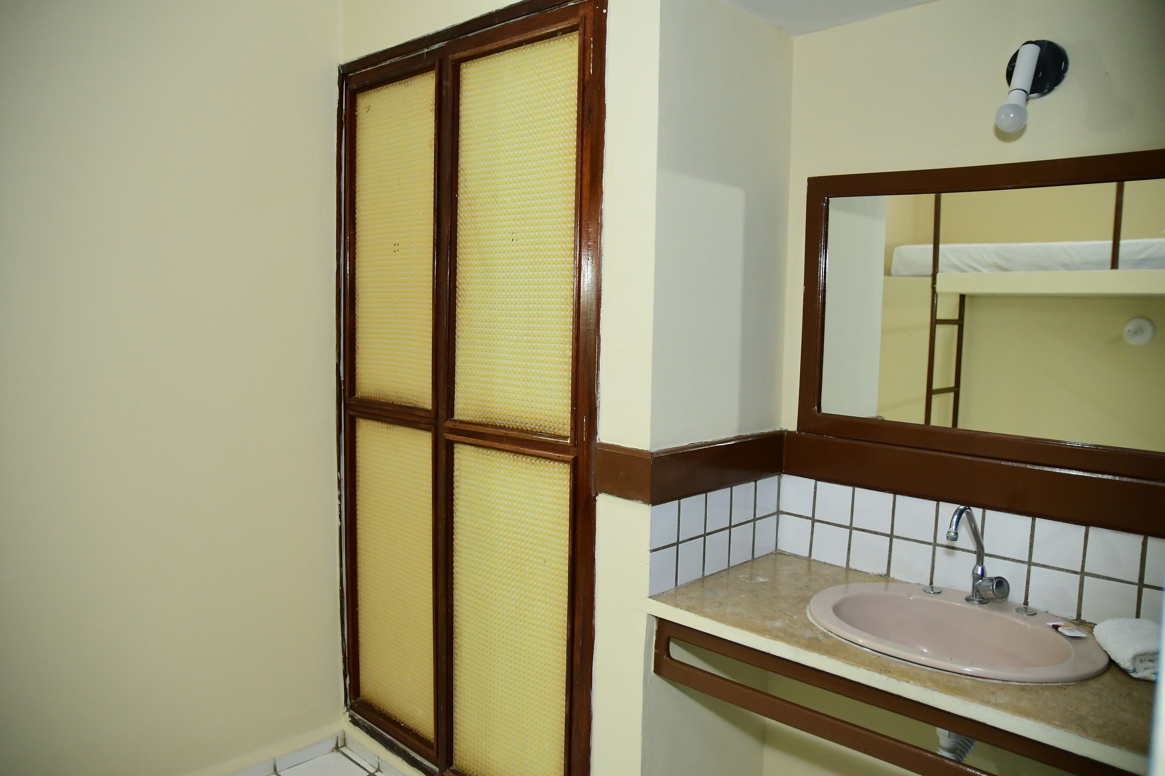 Un baño con lavamanos, espejo y ventana con marco de madera.