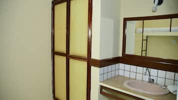 Un baño con lavamanos, espejo y ventana con marco de madera.