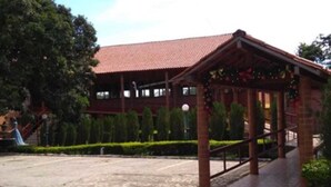 A building with a red-tiled roof, a covered walkway, and a paved entrance area. - Hotel Serrano (Martins)