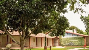 A building with a tiled roof, a grassy courtyard, and a mural on the wall. - Hotel Serrano (Martins)