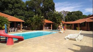 A pool area with a red slide, lounge chairs, and covered seating areas. - Hotel Serrano (Martins)