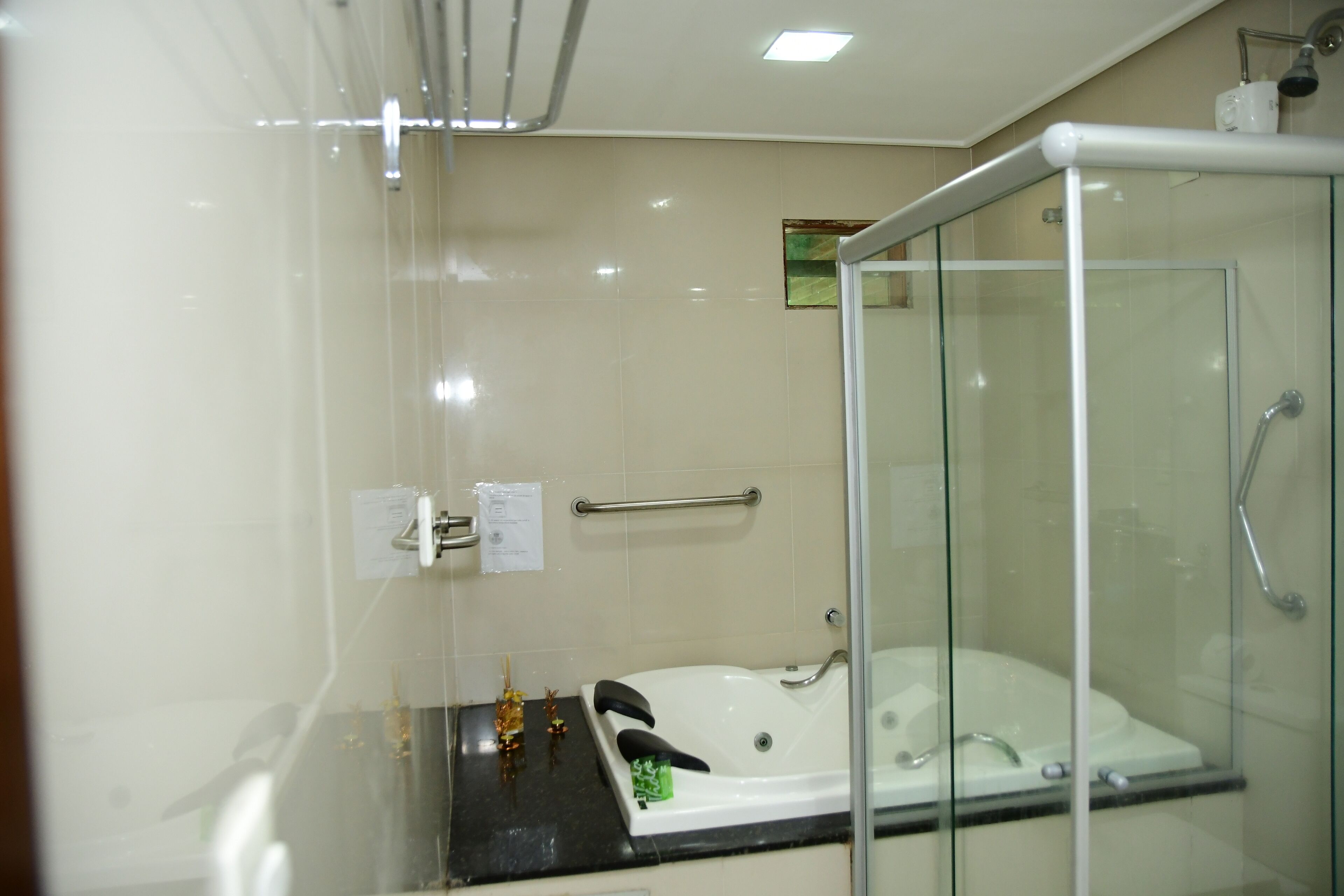 A modern bathroom with a glass-enclosed shower, a white bathtub, and a black countertop.