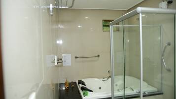 A modern bathroom with a glass-enclosed shower, a white bathtub, and a black countertop.