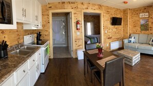 A compact, wood-paneled room with a kitchenette, a dining area, and a seating area.