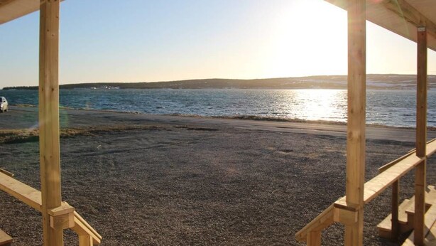 A wooden deck overlooking a beach with a clear view of the water and distant shoreline.