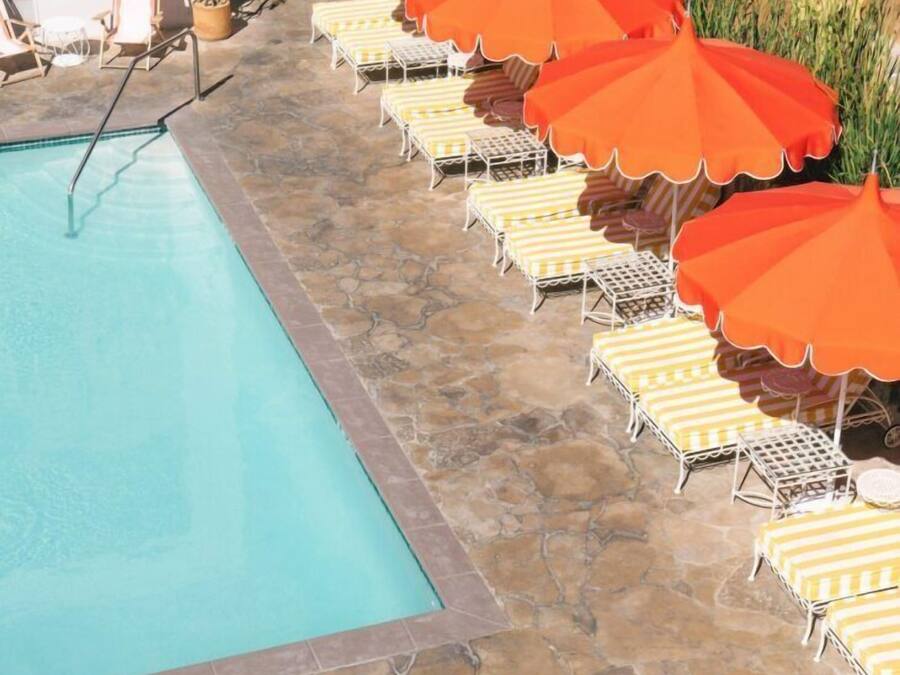 Ein Poolbereich mit Liegestühlen und orangefarbenen Sonnenschirmen.