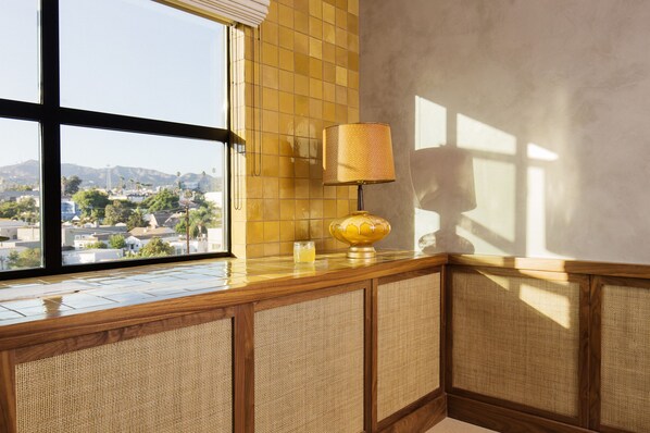 A corner with a window, a lamp, and a view of a cityscape.