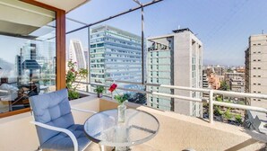 En balkon med et glasbord, en stol og en vase med blomster.