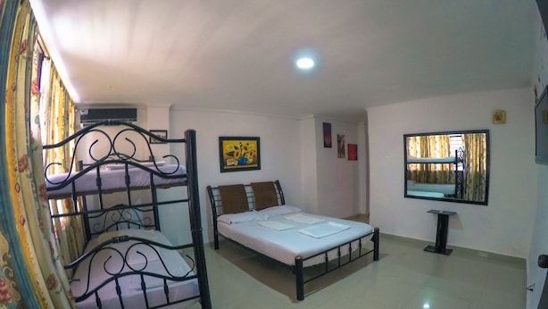 A room with bunk beds, a single bed, a small table, and a mirror on the wall. - Hostal El Exito (Santa Marta)