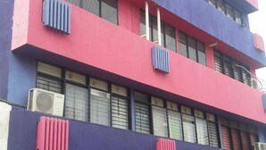 A multi-story building with a red and blue facade, large windows with blinds, and air conditioning units. - Hostal El Exito (Santa Marta)