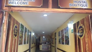 A hallway with signs reading "BIENVENIDOS WELCOME" and "HOSTAL BOUTIQUE". - Hostal El Exito (Santa Marta)