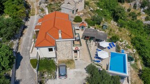 An aerial view of a property with a red-roofed building, a swimming pool, and a car parked in front. - Villa Makar with  infinity heated pool,gym,grill, 3 bedrooms,3 bathrooms (Dalmatia)