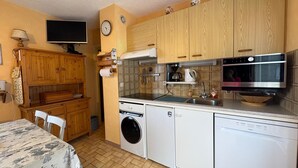 Une cuisine compacte avec des meubles en bois, un lave-linge, un lave-vaisselle et un four à micro-ondes.