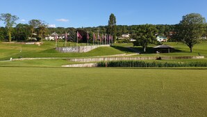 Un parcours de golf doté de structures en bois, de drapeaux et d’un pavillon.