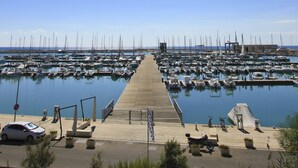 A marina with numerous boats docked, a wooden pier leading into the water, and a clear blue sky. - Levante, Holiday Home 100 metres from the sandy beach and near the centre (Marina di Ragusa)