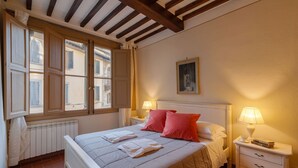 A bedroom with a large bed, two bedside lamps, a radiator, and a window with shutters. - Beautiful apartment for 4 guests with WIFI, A/C, TV and pets allowed (Cortona)