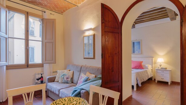 A cozy room with a sofa, a dining table with a bowl, and a bed with a nightstand. - Beautiful apartment for 4 guests with WIFI, A/C, TV and pets allowed (Cortona)