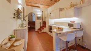 A kitchen with white cabinets, a microwave, and a sink. There is a staircase leading to another room. - Beautiful apartment for 4 guests with WIFI, A/C, TV and pets allowed (Cortona)