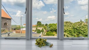 Ein Zimmer mit einem großen Fenster und Blick auf einen Garten und Gebäude.