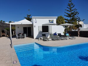 Un espace aménagé au bord de la piscine, avec des chaises longues et un petit bâtiment sur lequel est apposée une enseigne.