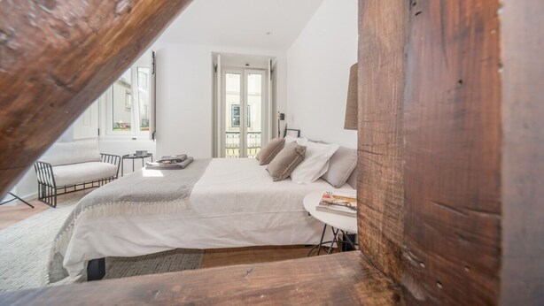Una camera da letto con un letto grande, un tavolino e una sedia. Si vede una finestra con vista all'esterno.