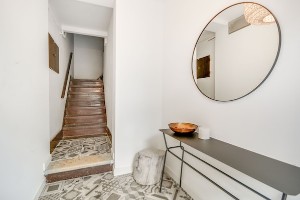 A staircase with patterned tiles, a round mirror, a wooden stool, and a small table with a bowl and candle. - Bairro House Lisbon Charming Suites (Lisbon)