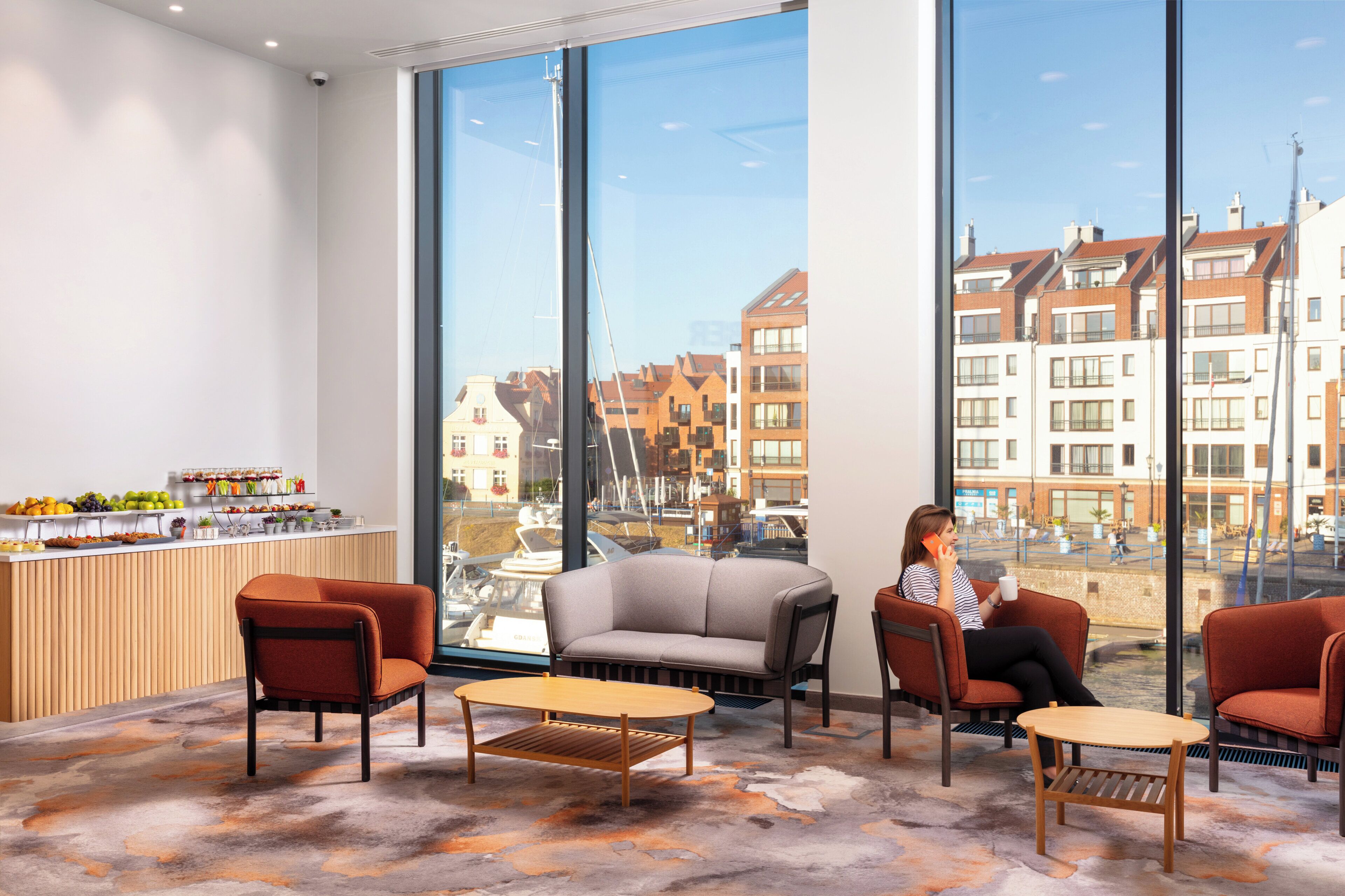 A modern interior with large windows, a reception area with a fruit display, and seating arrangements.