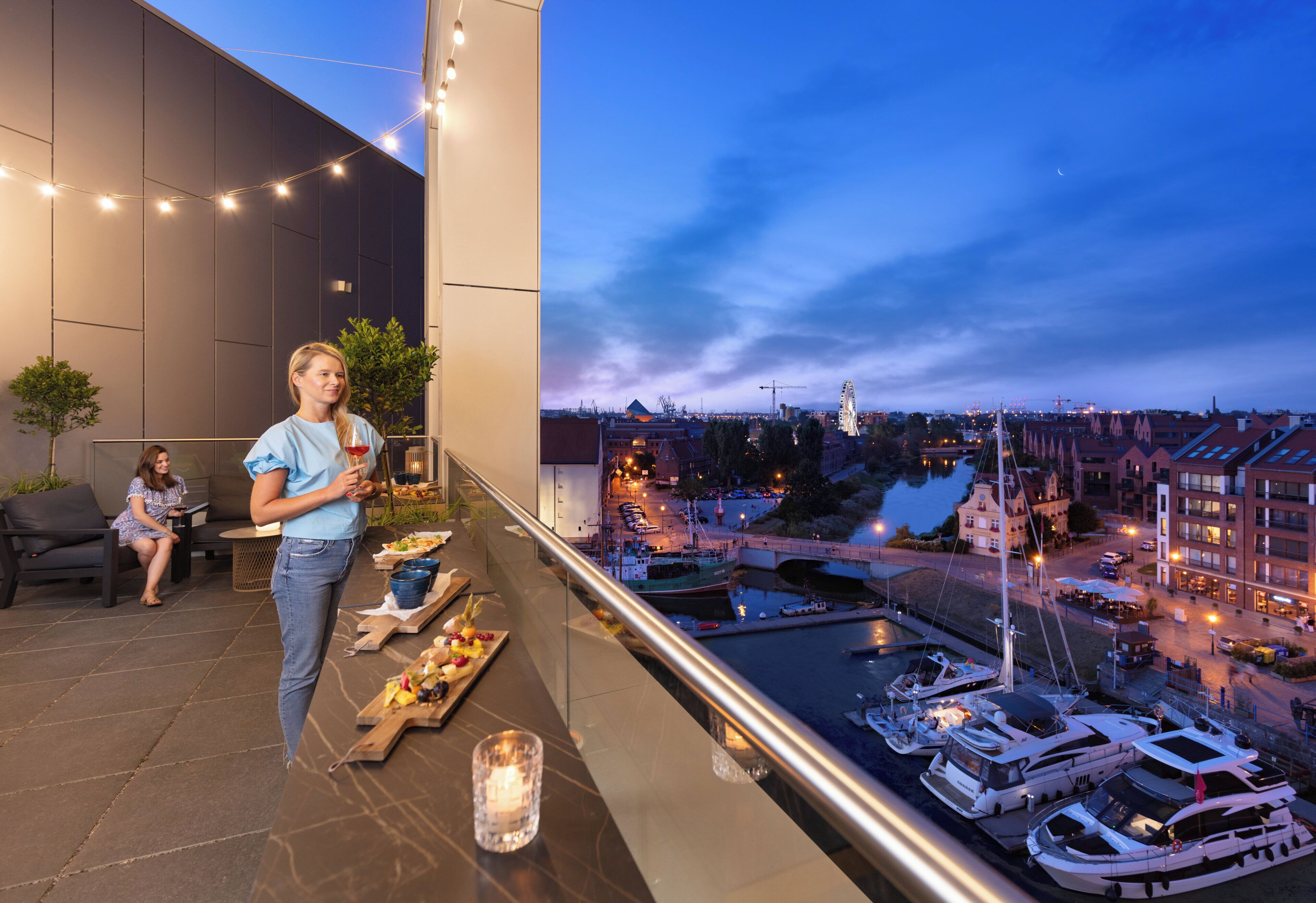 Ein Balkon mit Blick auf eine Stadtlandschaft, darunter ein Fluss und ein Riesenrad.