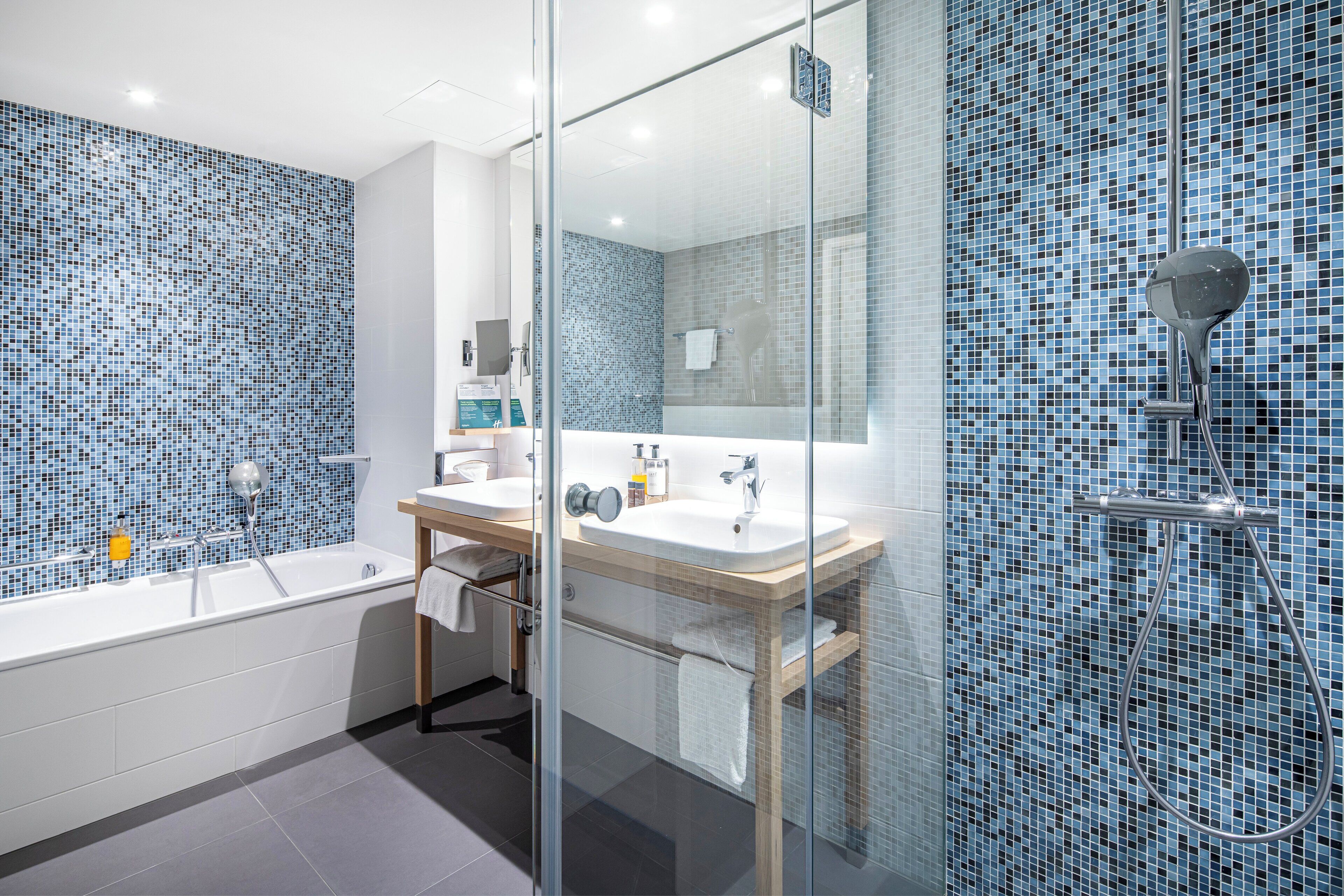 A modern bathroom with a glass-enclosed shower, a large bathtub, and a vanity with a mirror.