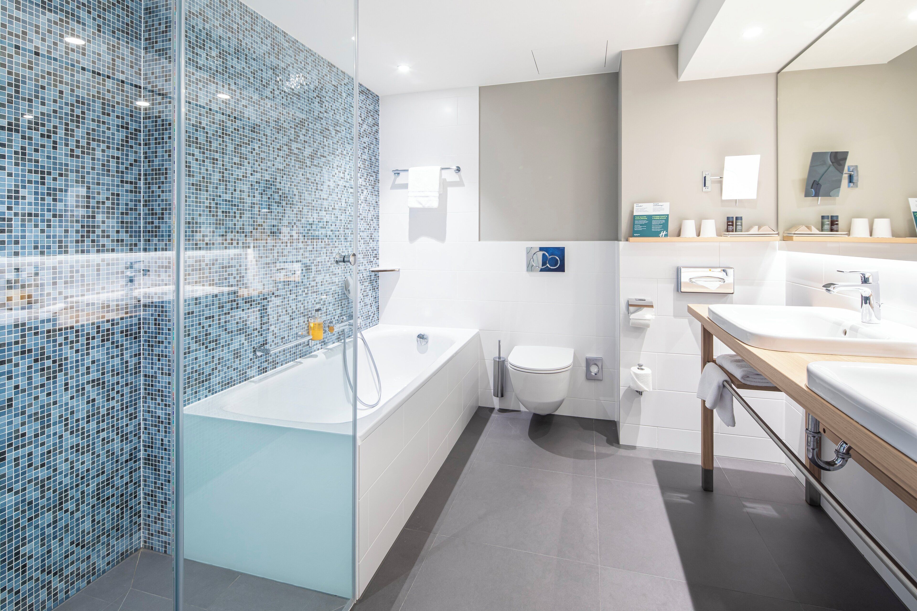 A modern bathroom with a glass shower enclosure, a freestanding bathtub, a toilet, and a vanity with a double sink.