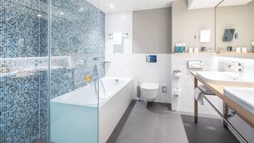 A modern bathroom with a glass shower enclosure, a freestanding bathtub, a toilet, and a vanity with a double sink.
