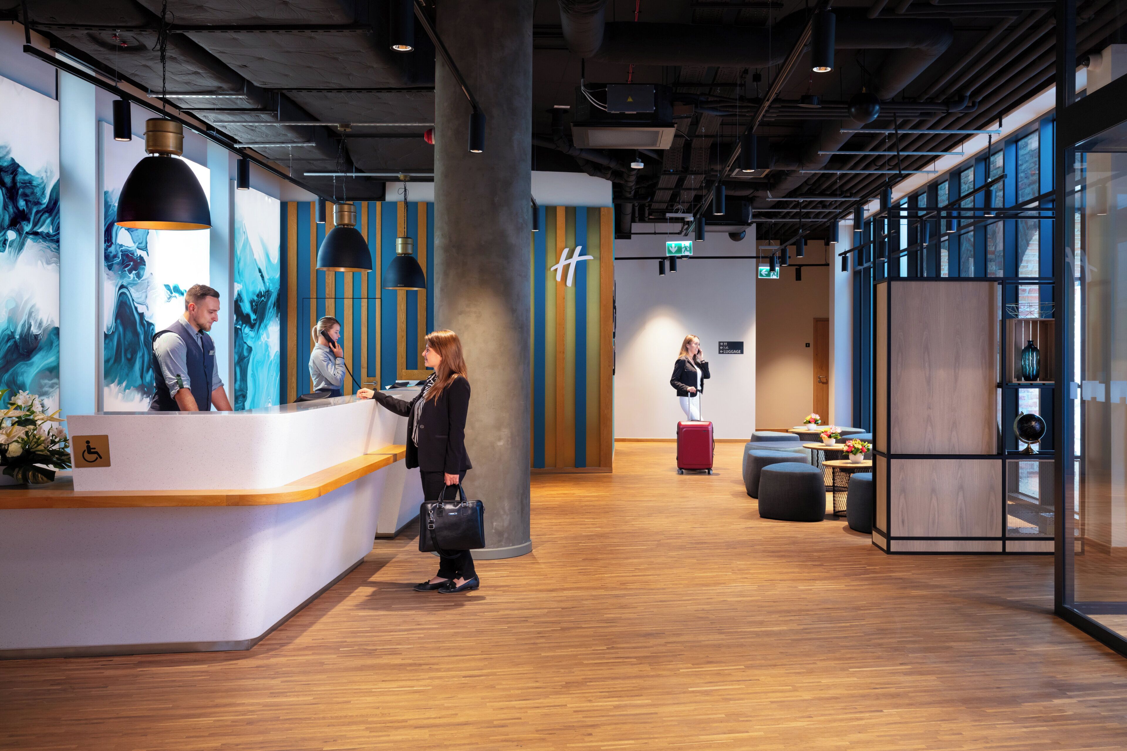 A reception area with a counter, a large pillar, and a seating area with tables and chairs.