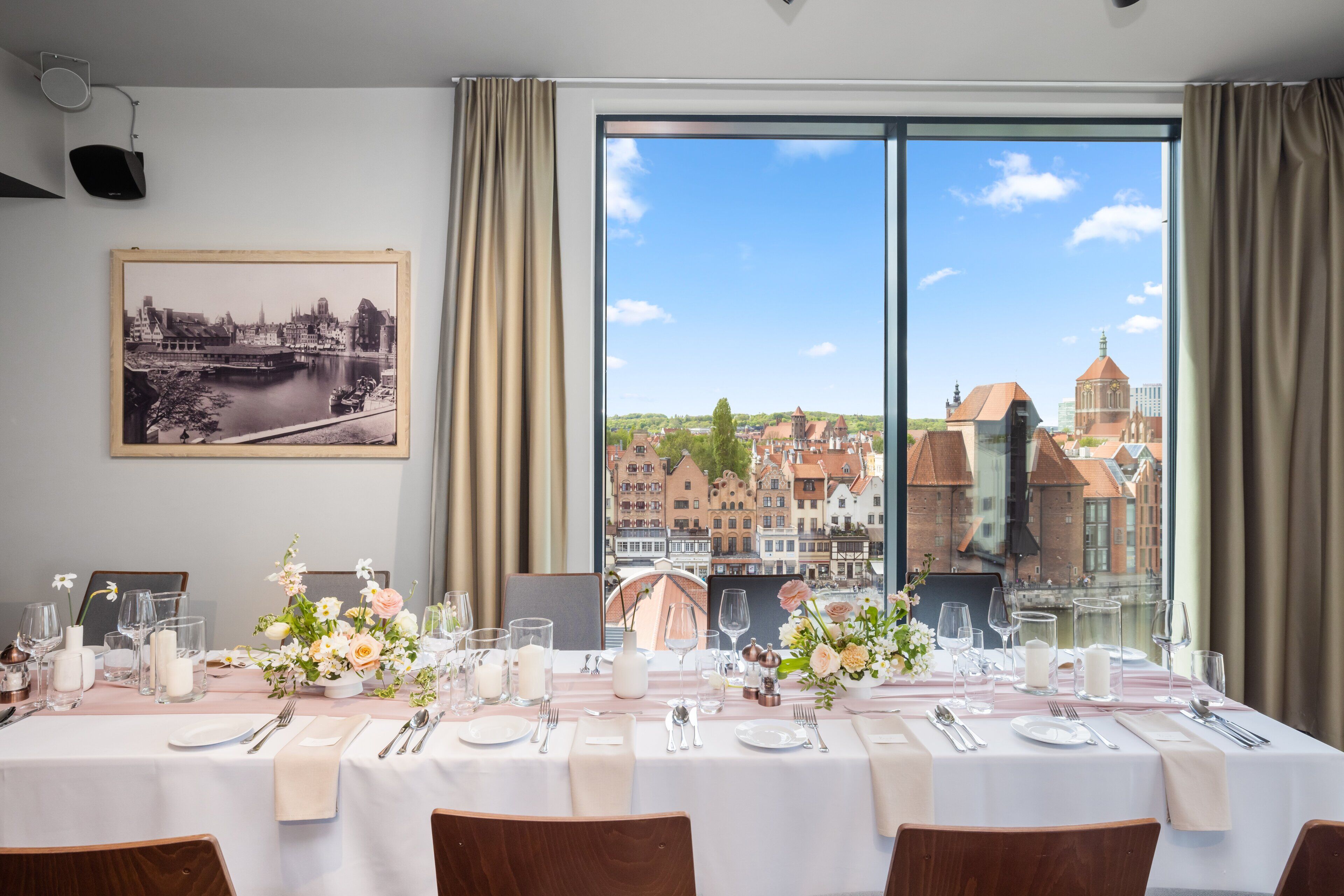 A dining table set for six with a view of a cityscape through large windows.