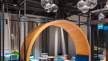 A modern interior with a circular wooden swing chair, wooden flooring, and hanging spherical light fixtures.