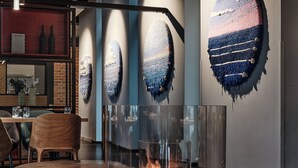 A modern interior with a round wooden table, a glass-enclosed fireplace, and abstract wall art. - Holiday Inn Gdansk - City Centre by IHG (Gdansk)
