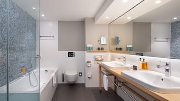 A modern bathroom with a glass-enclosed shower, a white toilet, and a vanity with two sinks and a mirror.