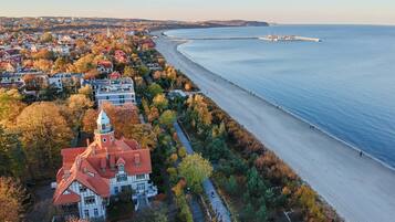 An aerial view of a coastal town with a prominent church, a beach, and a pier extending into the sea.