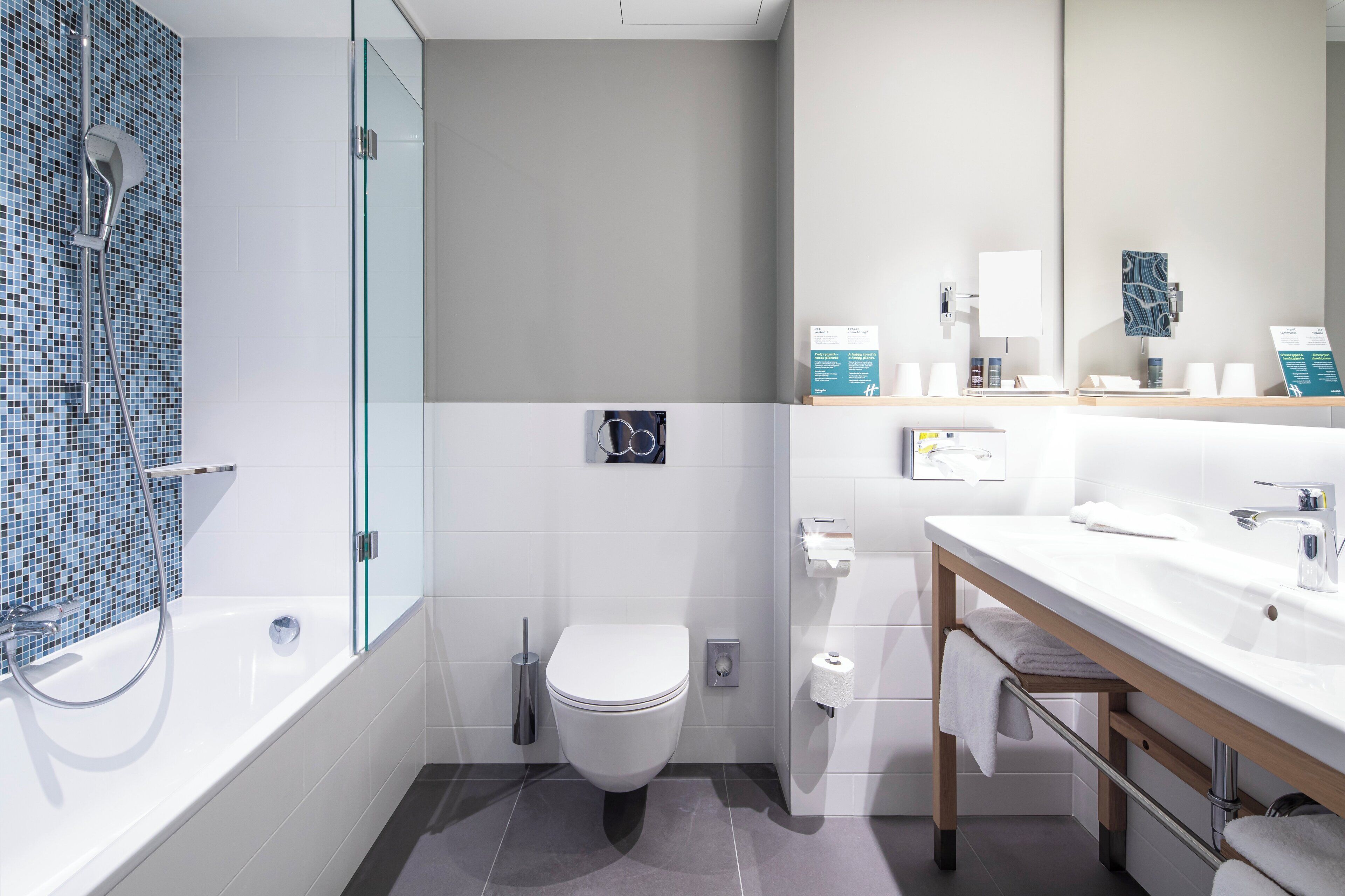 Une salle de bain moderne avec une douche à parois de verre, des toilettes blanches et un meuble-lavabo avec un miroir.