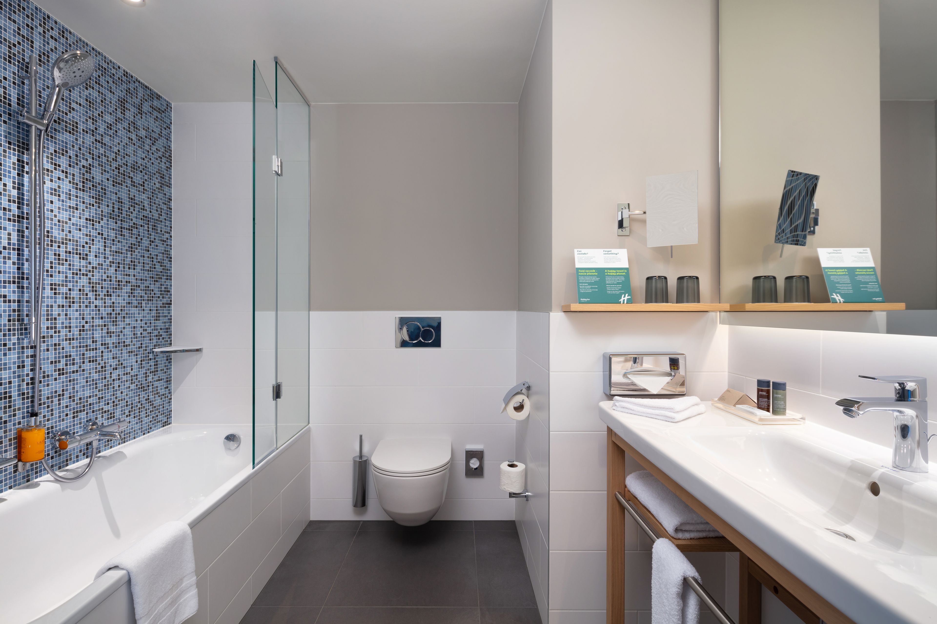 A modern bathroom with a glass-enclosed shower, a white toilet, and a vanity with a mirror.