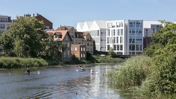 En flod där folk åker kajak, omgiven av byggnader med varierande arkitektur.
