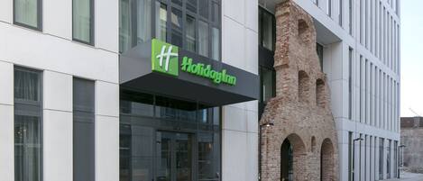 Un hotel Holiday Inn con fachada moderna, amplios ventanales y un característico arco de ladrillo.