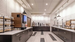 A modern kitchen with dark cabinetry, a central island, and a coffee machine.