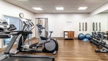 A fitness center with treadmills, elliptical machines, free weights, and exercise balls.