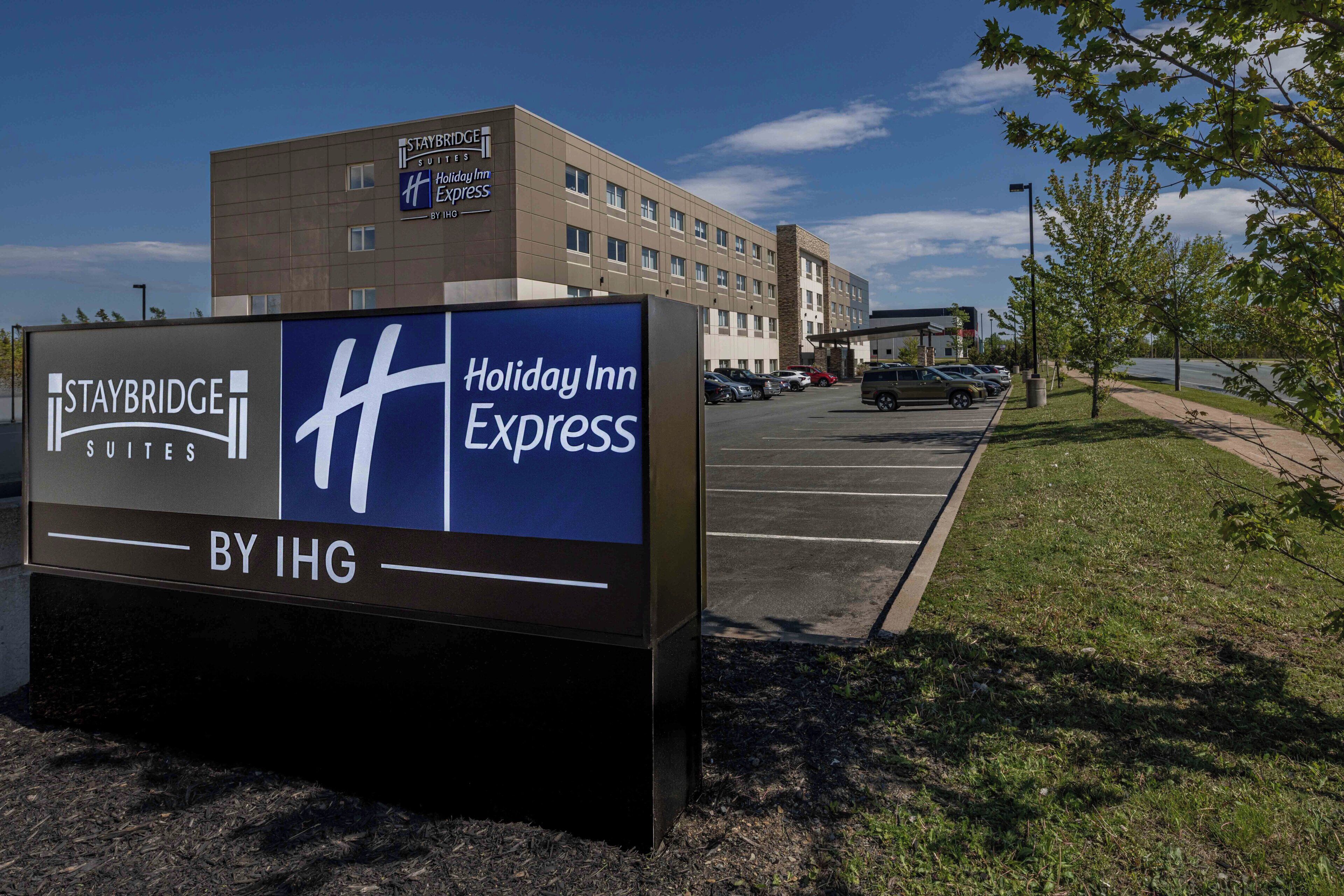 A Staybridge Suites Holiday Inn Express sign with a parking lot and a building in the background.