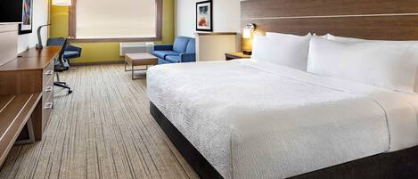 A hotel room with a large bed, a desk, a chair, and a TV.